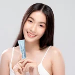 Woman holding Emolene Cream for oily skin with a smile